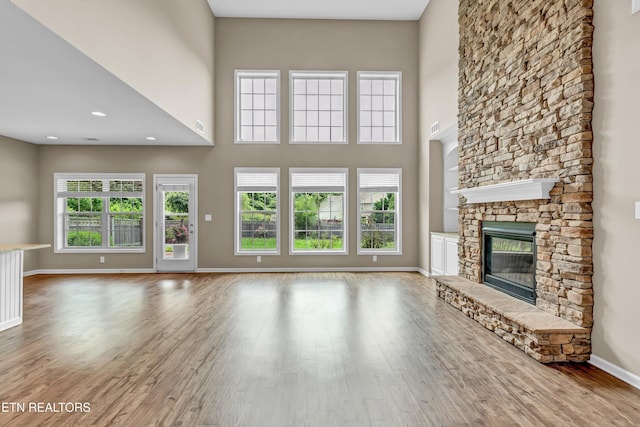 2017 Gusty Wind Ln, Knoxville, TN 37932 - unfurnished living room featuring wood finished floors, a stone fireplace, and a towering ceiling