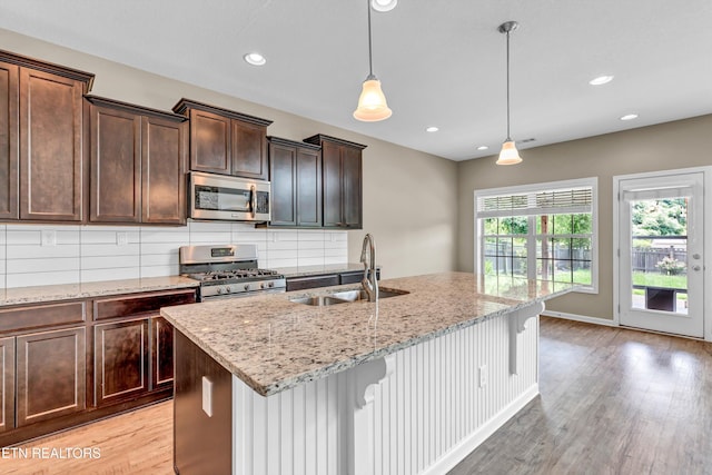 2017 Gusty Wind Ln, Knoxville, TN 37932 - kitchen featuring appliances with stainless steel finishes, light wood-style floors, decorative backsplash, light stone counters, and a breakfast bar area