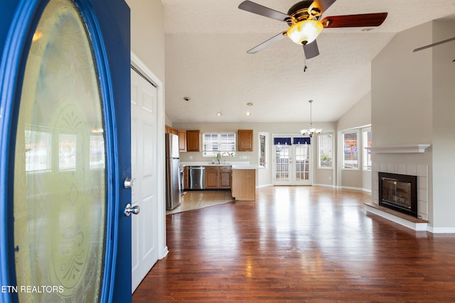 541 Pebble Creek Rd, Knoxville, TN 37918 - unfurnished living room with wood finished floors, ceiling fan, lofted ceiling, a tiled fireplace, and a chandelier