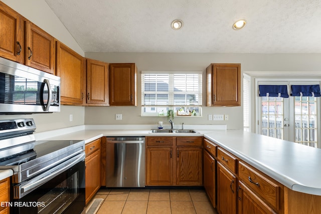 541 Pebble Creek Rd, Knoxville, TN 37918 - kitchen featuring stainless steel appliances, brown cabinets, plenty of natural light, a textured ceiling, and a peninsula