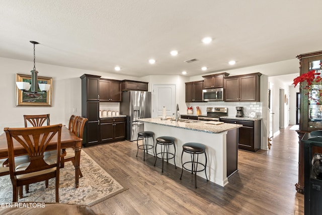 1426 Mesquite Dr, Sevierville, TN 37876 - kitchen with stainless steel appliances, dark brown cabinetry, a kitchen breakfast bar, dark wood-type flooring, and recessed lighting