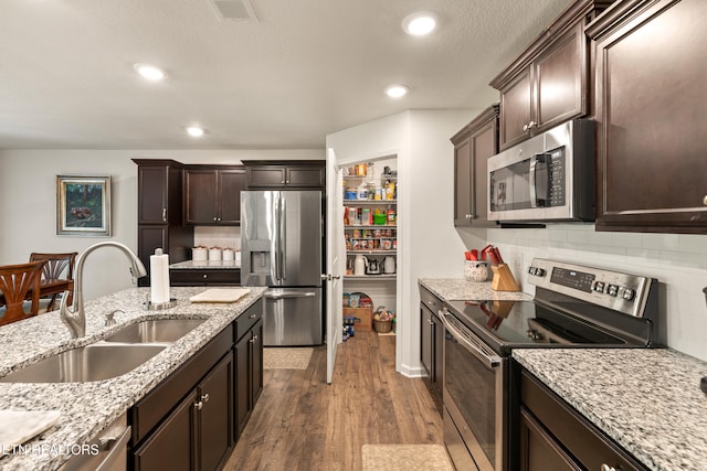 1426 Mesquite Dr, Sevierville, TN 37876 - kitchen with appliances with stainless steel finishes, dark brown cabinets, dark wood-style floors, tasteful backsplash, and light stone counters