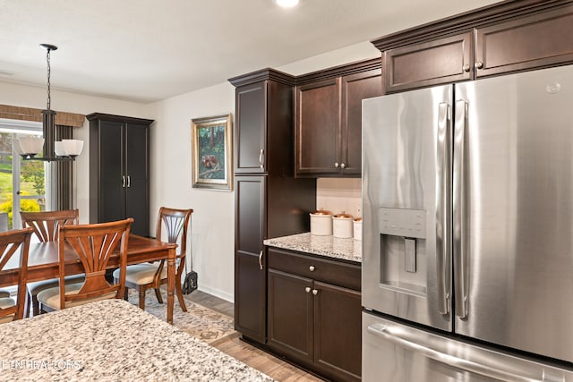 1426 Mesquite Dr, Sevierville, TN 37876 - kitchen featuring stainless steel refrigerator with ice dispenser, light wood-style flooring, dark brown cabinets, light stone counters, and hanging light fixtures