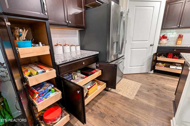 1426 Mesquite Dr, Sevierville, TN 37876 - kitchen with dark brown cabinets, light wood-style floors, stainless steel fridge, backsplash, and light stone countertops