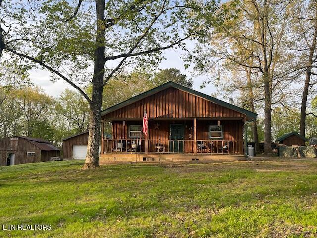 4016 Retro Hughes Rd, Graysville, TN 37338 - rear view of property with a porch, a lawn, a detached garage, and board and batten siding