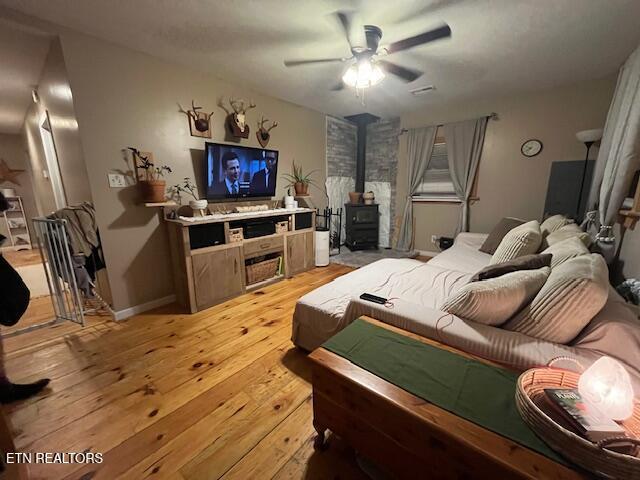 4016 Retro Hughes Rd, Graysville, TN 37338 - bedroom featuring a wood stove, light wood-style floors, and ceiling fan