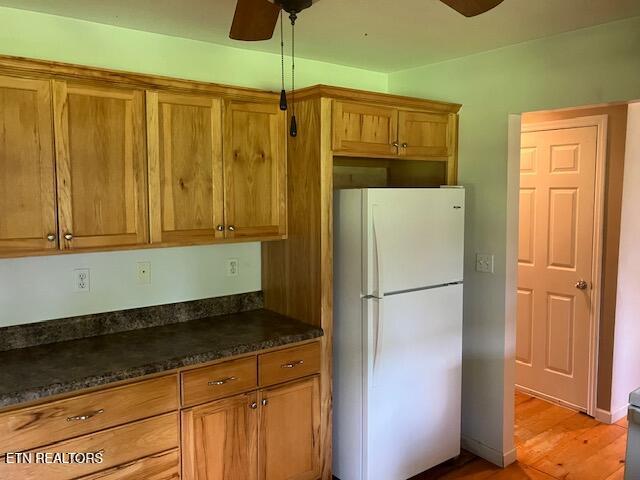 4016 Retro Hughes Rd, Graysville, TN 37338 - kitchen with freestanding refrigerator, ceiling fan, brown cabinets, dark countertops, and light wood-style floors