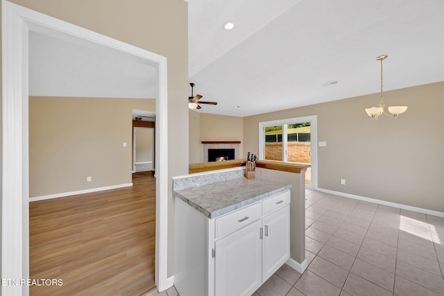 8040 Walt Way, Corryton, TN 37721 - kitchen with ceiling fan, white cabinetry, open floor plan, light countertops, and a fireplace with raised hearth