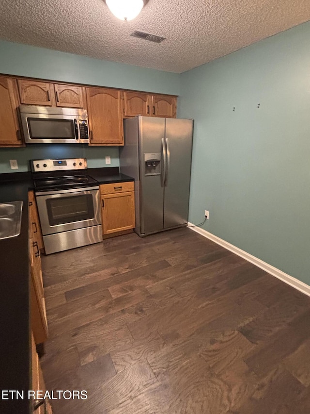 8022 Intervale Way, Powell, TN 37849 - kitchen with stainless steel appliances, dark countertops, a textured ceiling, brown cabinets, and dark wood-style flooring