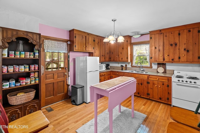 5400 Parkdale Rd, Knoxville, TN 37912 - kitchen with white appliances, a chandelier, light wood finished floors, and brown cabinets