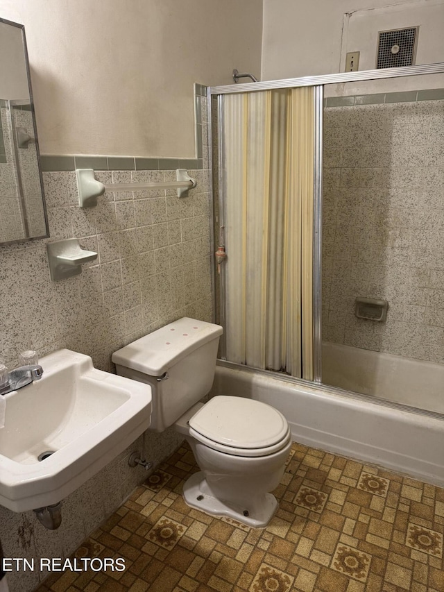2101 NW Chillicothe St, Knoxville, TN 37921 - bathroom featuring enclosed tub / shower combo, brick patterned flooring, wainscoting, and tile walls