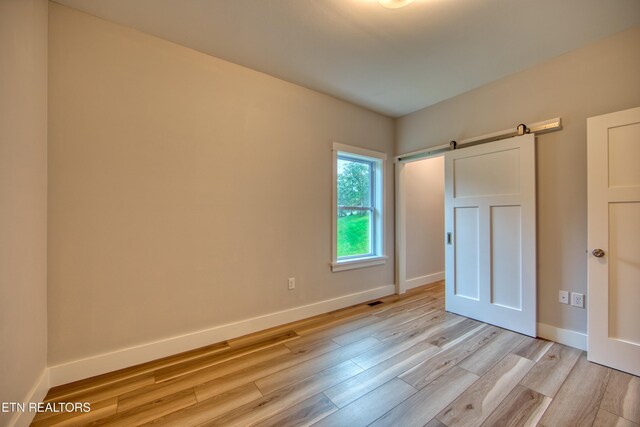 760 Rockview Rd, Jamestown, TN 38556 - unfurnished bedroom featuring light wood-type flooring and a barn door