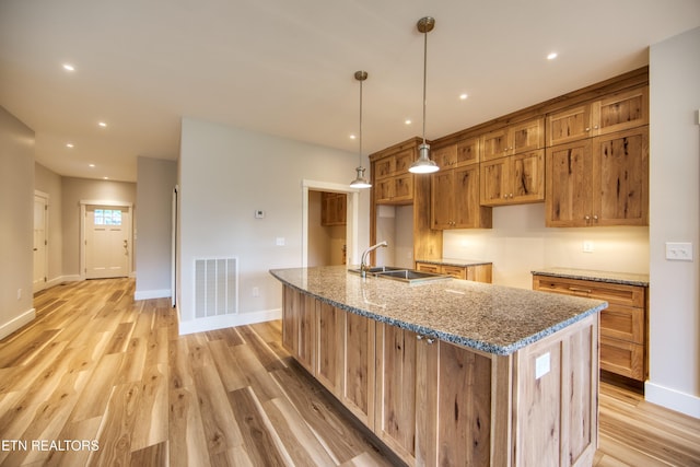 760 Rockview Rd, Jamestown, TN 38556 - kitchen with a kitchen island with sink, light wood-type flooring, brown cabinetry, stone countertops, and recessed lighting