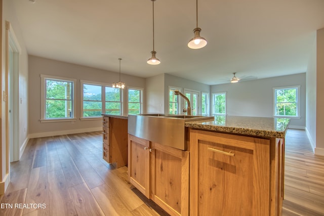 760 Rockview Rd, Jamestown, TN 38556 - kitchen featuring light wood-type flooring, a kitchen island with sink, decorative light fixtures, light stone countertops, and a chandelier