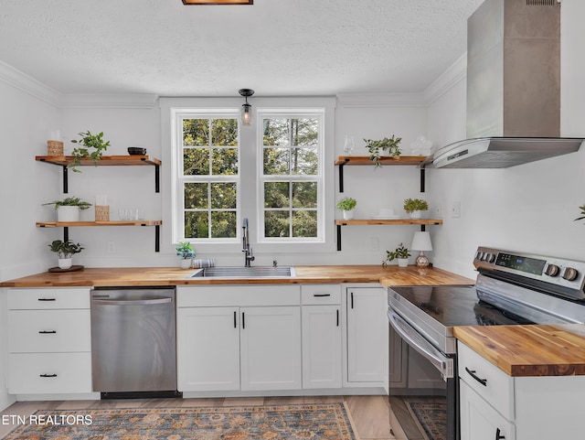 1100 Cedar Ln, Knoxville, TN 37912 - kitchen featuring butcher block counters, appliances with stainless steel finishes, wall chimney range hood, a textured ceiling, and crown molding