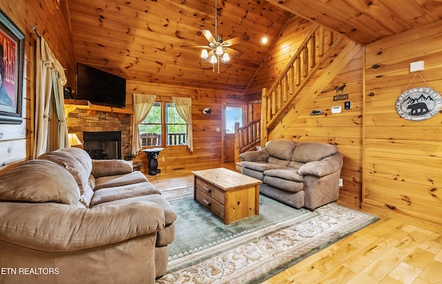 1930 Orchard Dr, Sevierville, TN 37876 - living room featuring stairs, lofted ceiling, wood finished floors, wooden walls, and a stone fireplace