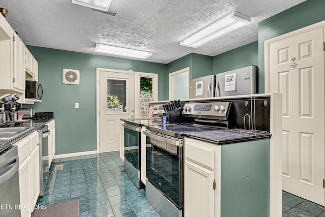 3950 Castle Rd, Gatlinburg, TN 37738 - kitchen featuring stainless steel appliances, dark countertops, a textured ceiling, white cabinets, and dark tile patterned flooring