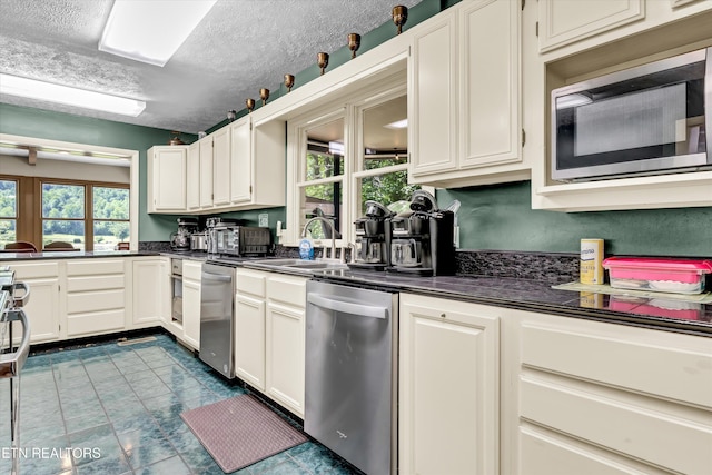 3950 Castle Rd, Gatlinburg, TN 37738 - kitchen with stainless steel appliances, dark countertops, white cabinets, and a textured ceiling