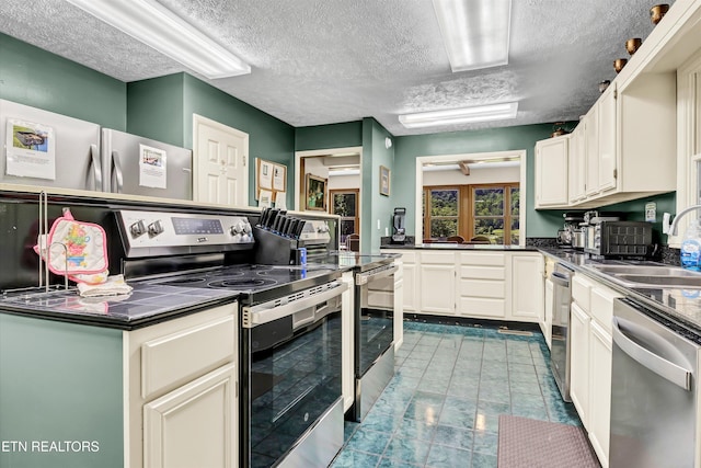 3950 Castle Rd, Gatlinburg, TN 37738 - kitchen with stainless steel appliances, dark countertops, a textured ceiling, and white cabinets