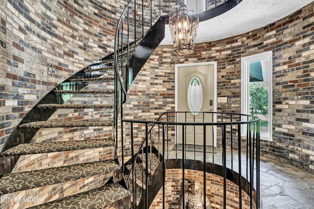 3950 Castle Rd, Gatlinburg, TN 37738 - stairs featuring brick wall, a chandelier, and stone tile flooring