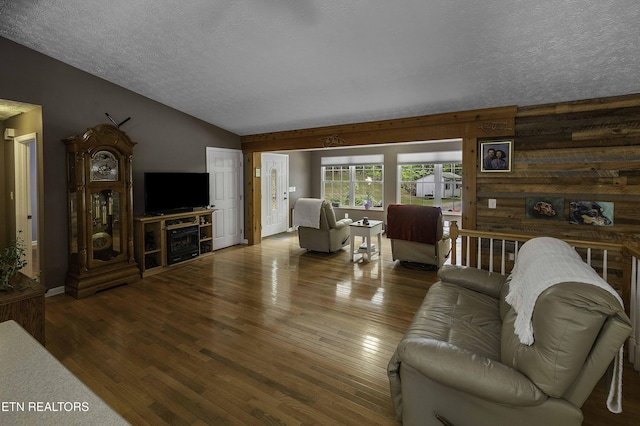 113 Skyland Ln, Powell, TN 37849 - living area with wood finished floors, a textured ceiling, vaulted ceiling, a fireplace, and wood walls