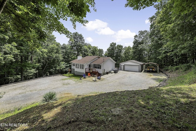 113 Skyland Ln, Powell, TN 37849 - view of front of home featuring an outbuilding, driveway, a detached carport, a view of trees, and a chimney