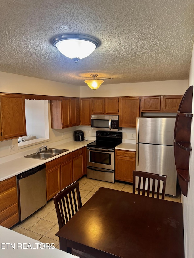 7925 Eldin Way, Powell, TN 37849 - kitchen with stainless steel appliances, a textured ceiling, light tile patterned flooring, brown cabinetry, and light countertops