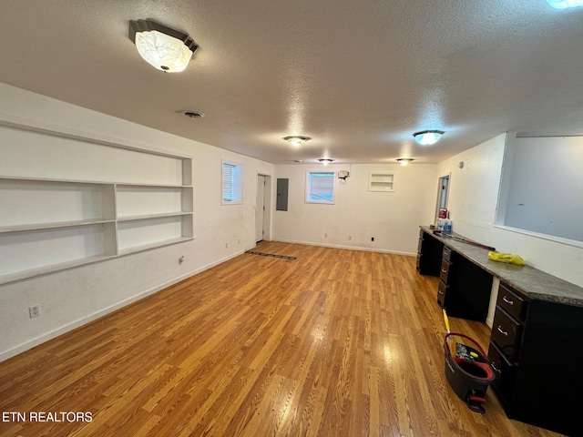 5521 S York Hwy, Grimsley, TN 38565 - unfurnished living room with a textured ceiling, light wood-type flooring, electric panel, and built in shelves