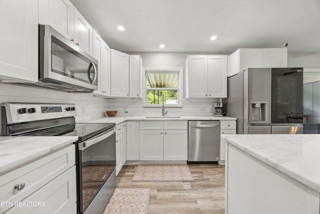 3408 Hackberry Rd, Knoxville, TN 37931 - kitchen with appliances with stainless steel finishes, light wood finished floors, white cabinetry, recessed lighting, and light stone counters