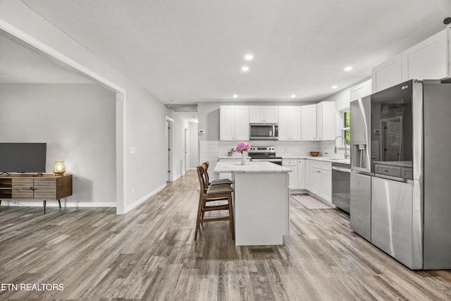 3408 Hackberry Rd, Knoxville, TN 37931 - kitchen featuring appliances with stainless steel finishes, a kitchen island, white cabinetry, light wood-type flooring, and tasteful backsplash