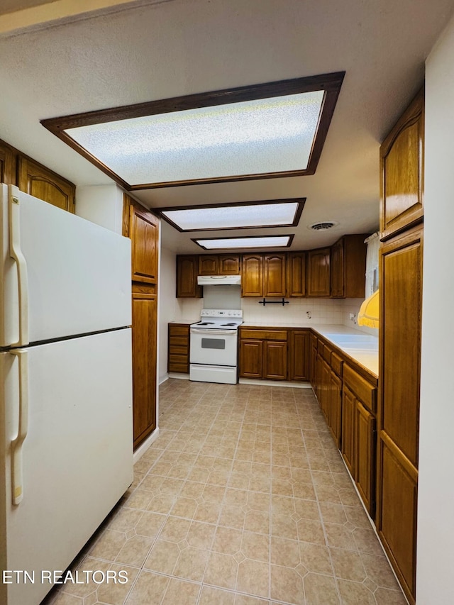 160 Clevenger Cut Off Rd, Newport, TN 37821 - kitchen with white appliances, under cabinet range hood, light countertops, brown cabinets, and light tile patterned floors
