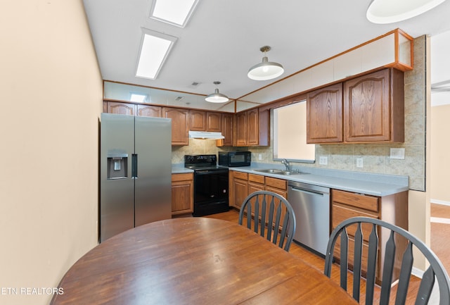 8016 Stablegate Way, Powell, TN 37849 - kitchen with black appliances, under cabinet range hood, decorative backsplash, brown cabinets, and light countertops