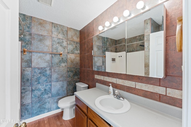 8016 Stablegate Way, Powell, TN 37849 - bathroom featuring tile walls, vanity, wood finished floors, tiled shower, and a textured ceiling