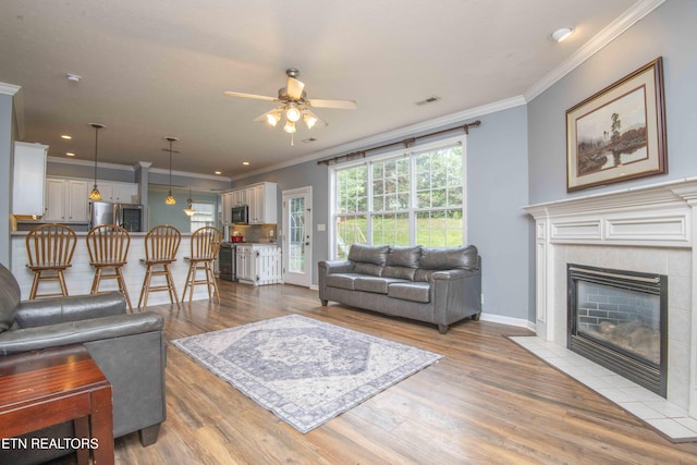 1223 Walnut Branch Ln, Knoxville, TN 37922 - living room featuring a ceiling fan, a tile fireplace, light wood-style flooring, crown molding, and recessed lighting
