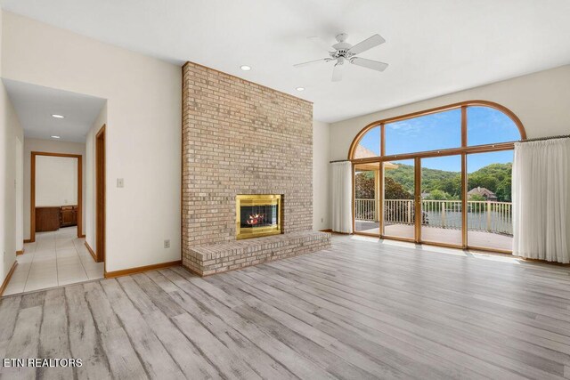 136 Oostagala Dr, Loudon, TN 37774 - unfurnished living room featuring wood finished floors, ceiling fan, a fireplace, recessed lighting, and a water view