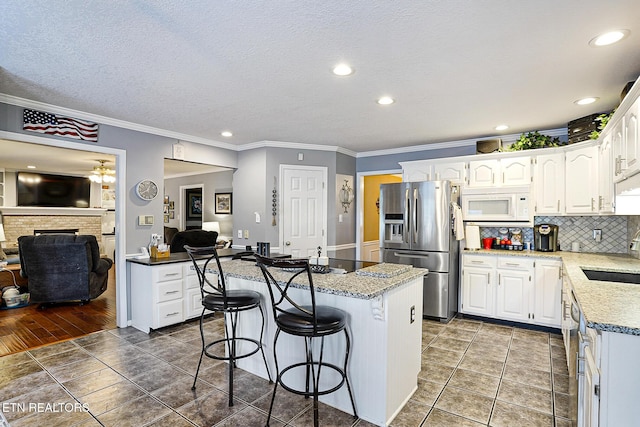 7110 Royal Springs Blvd, Knoxville, TN 37918 - kitchen with stainless steel fridge, white microwave, a fireplace, a breakfast bar, and a kitchen island