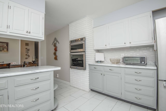 506 Blockhouse Valley Rd, Clinton, TN 37716 - kitchen with stainless steel double oven, white cabinetry, light marble finish floors, tasteful backsplash, and freestanding refrigerator