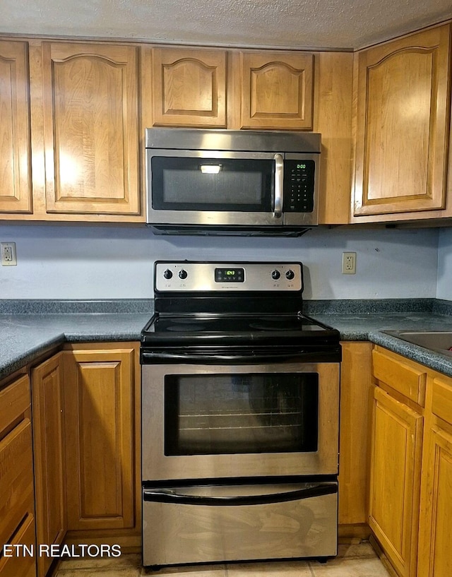 1081 Cove Rd Unit 623, Sevierville, TN 37876 - kitchen featuring stainless steel appliances, dark countertops, brown cabinets, and a textured ceiling