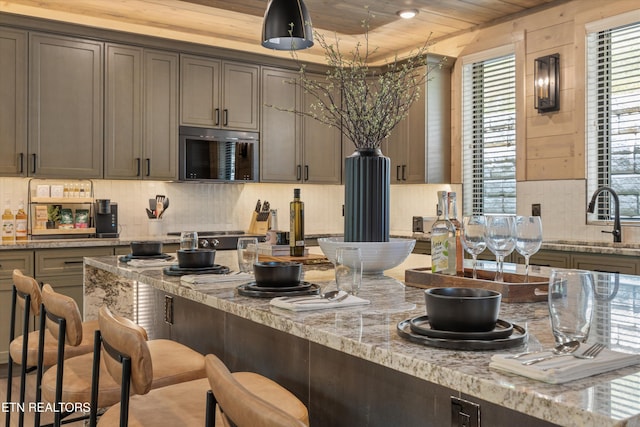 1646 Bear Valley Rd, Sevierville, TN 37876 - kitchen featuring stainless steel microwave, plenty of natural light, a kitchen bar, wooden ceiling, and light stone counters