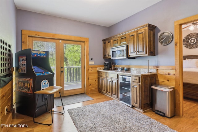 3206 Falling Leaf Way, Pigeon Forge, TN 37863 - kitchen with beverage cooler, stainless steel microwave, light wood-style floors, brown cabinets, and light stone countertops