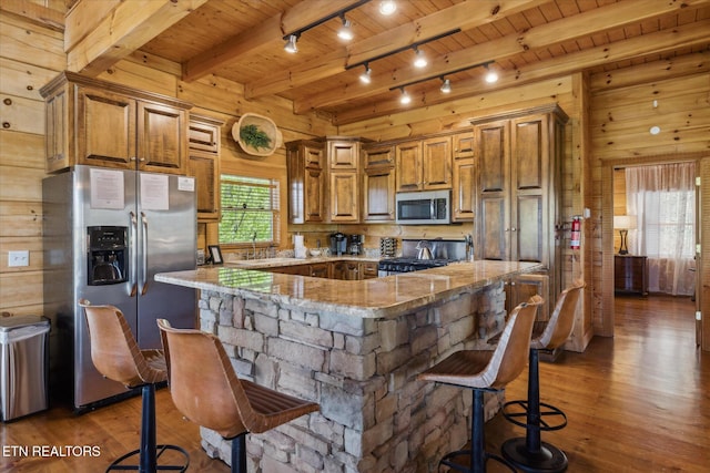 3206 Falling Leaf Way, Pigeon Forge, TN 37863 - kitchen with stainless steel appliances, hardwood / wood-style flooring, light stone counters, brown cabinets, and a wood ceiling with exposed beams