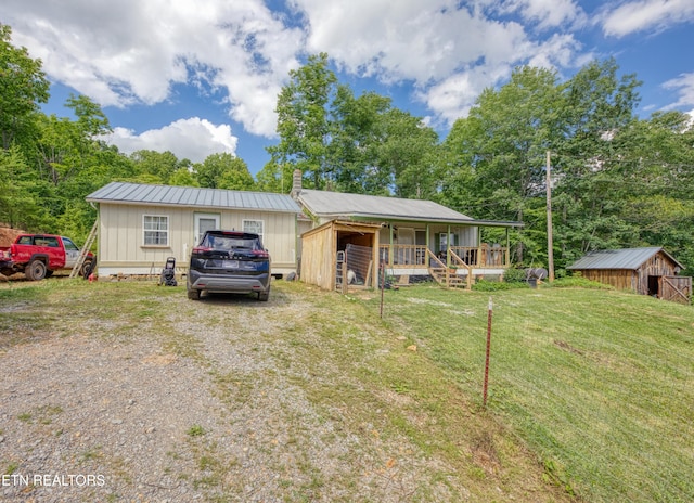 5271 Vardy Blackwater Rd, Sneedville, TN 37869 - view of front of property featuring a front lawn, an outdoor structure, a chimney, board and batten siding, and covered porch