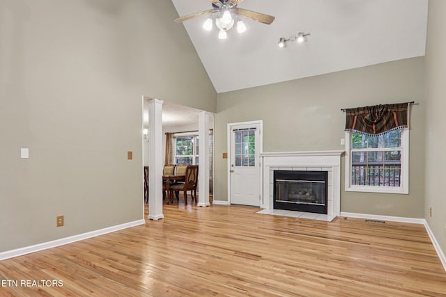317 Fallen Oak Cir, Seymour, TN 37865 - unfurnished living room with high vaulted ceiling, a ceiling fan, ornate columns, light wood-type flooring, and a tiled fireplace
