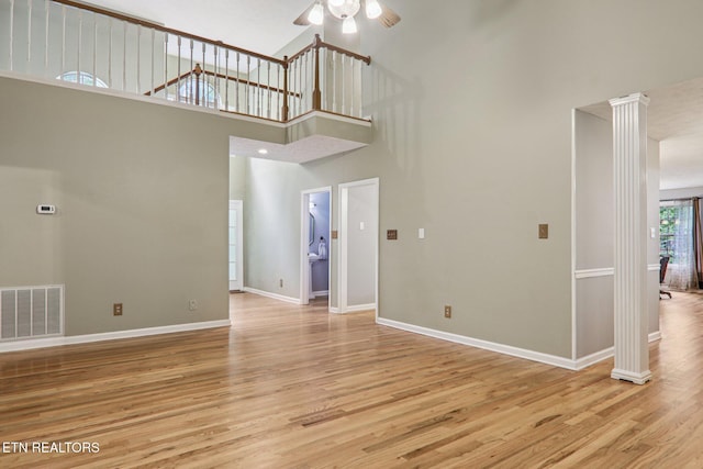 317 Fallen Oak Cir, Seymour, TN 37865 - unfurnished living room featuring ornate columns, wood finished floors, a ceiling fan, and a towering ceiling