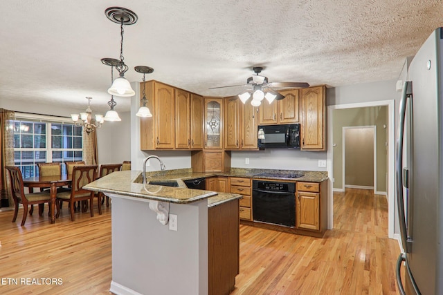317 Fallen Oak Cir, Seymour, TN 37865 - kitchen featuring black appliances, a peninsula, brown cabinetry, light wood finished floors, and a textured ceiling