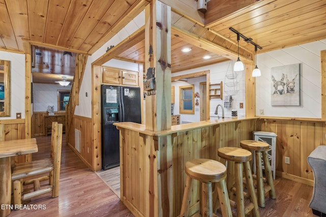 3014 N Clear Fork Rd, Sevierville, TN 37862 - kitchen with wooden walls, black fridge, wooden ceiling, light wood finished floors, and a kitchen bar