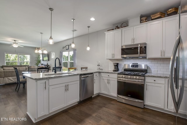 11944 Cordial Ln, Knoxville, TN 37932 - kitchen featuring appliances with stainless steel finishes, a peninsula, open floor plan, white cabinetry, and tasteful backsplash