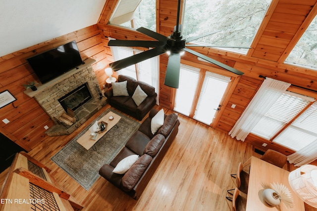 3653 Country Pines Way, Sevierville, TN 37876 - living room featuring wooden walls, a stone fireplace, wood finished floors, ceiling fan, and a high ceiling