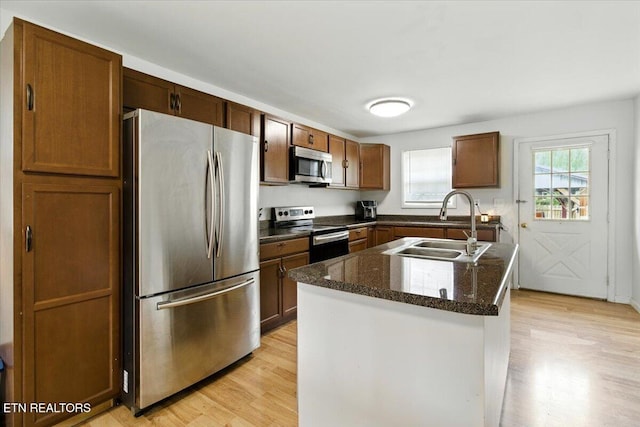 409 Meadow Ln, Middlesboro, KY 40965 - kitchen featuring appliances with stainless steel finishes, light wood-style floors, a center island with sink, and dark stone countertops