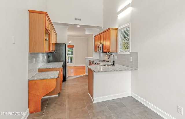 933 Gothic Manor Way, Knoxville, TN 37923 - kitchen featuring stainless steel appliances, tasteful backsplash, a peninsula, light tile patterned floors, and ornamental molding